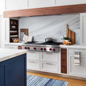 marble slap backsplash behind stove with custom range hood and beige cabinets