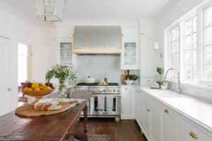 white kitchen with wood island and commercial hood